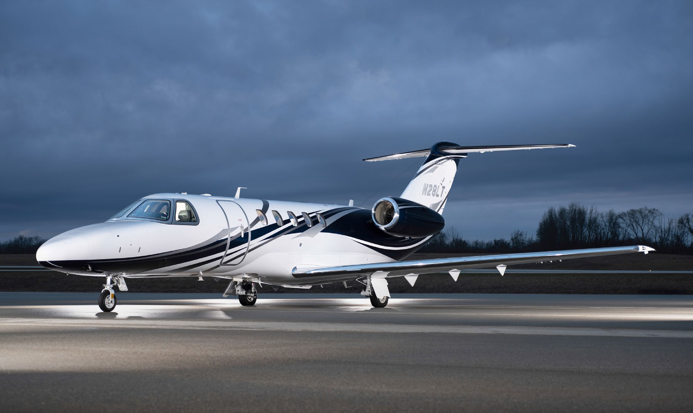 A Cessna Citation CJ4 sits on a runway at night.